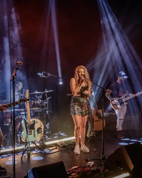 Maddison A and her band on stage with spotlights