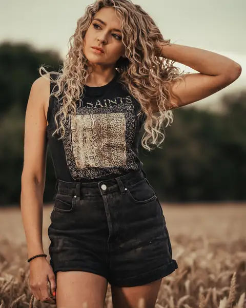 Maddison A standing in a wheat field at sunset